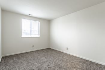 A room with a carpeted floor and a window at Pheasant Run Apartments, Indiana, 47909